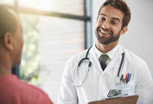 Shot of a male doctor talking with a patient in a hospital lobby
